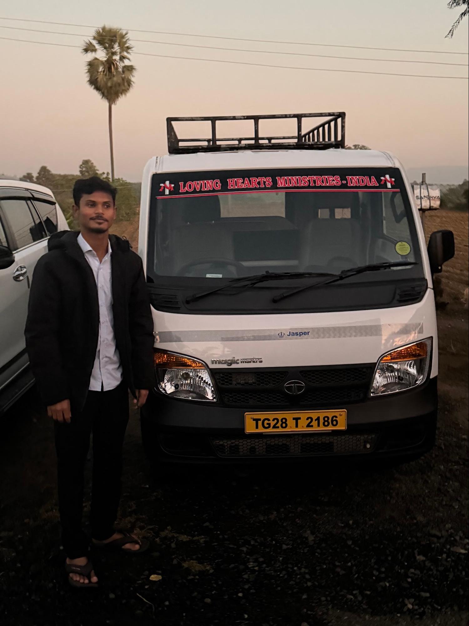 Local leader beside the Loving Hearts Ministries ministry vehicle