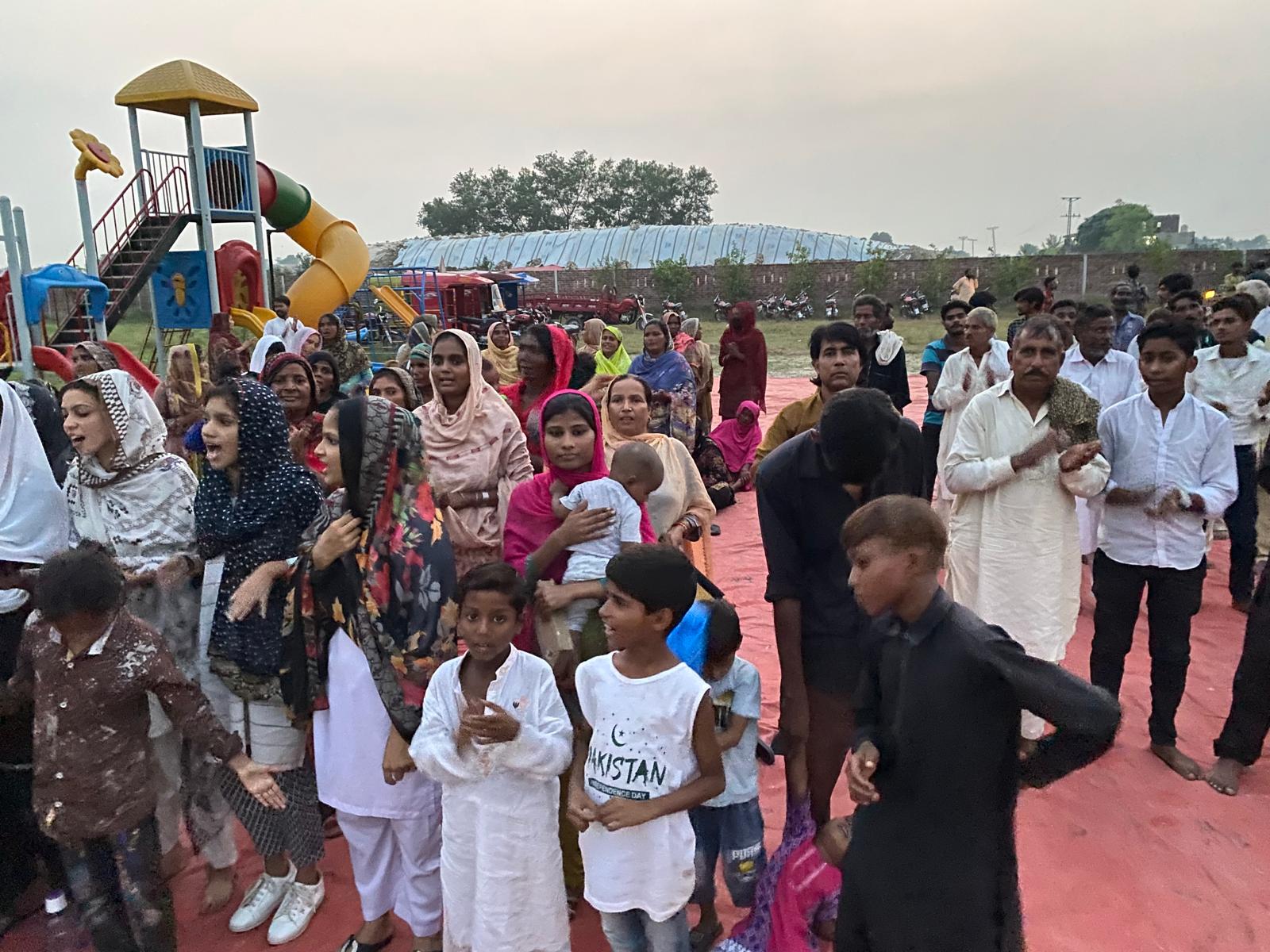 A joyful outdoor gathering of families and children in Pakistan
