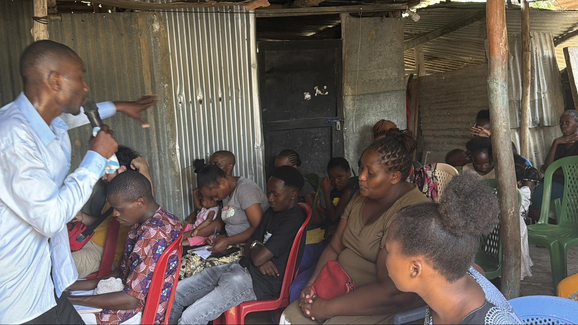 Pastor teaching a congregation gathered under a simple shelter