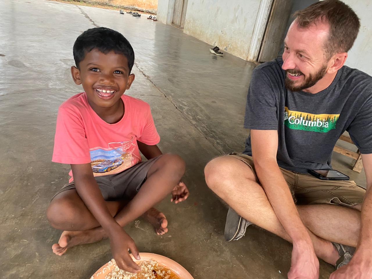Team member sharing a meal with a smiling boy