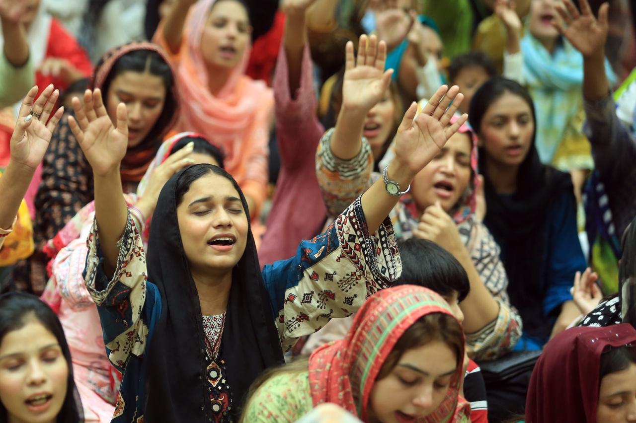Women worshiping with hands raised during a gathering in Pakistan
