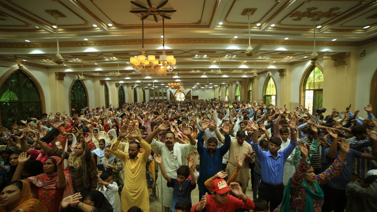A large congregation raising hands in worship in Pakistan
