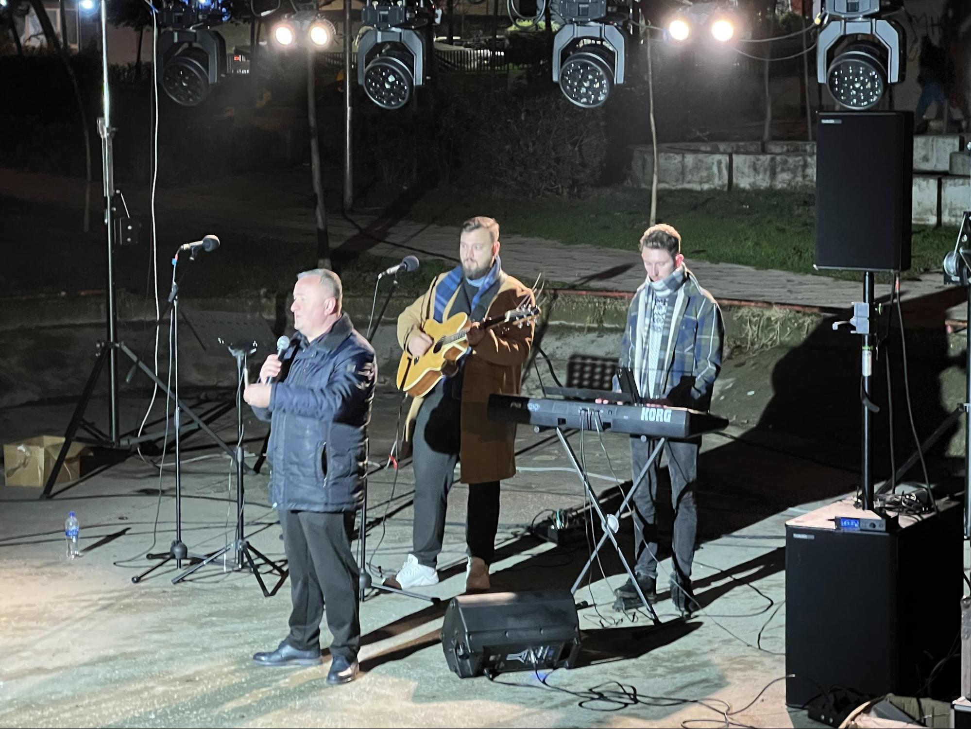 Outdoor evening worship and preaching event with a live band