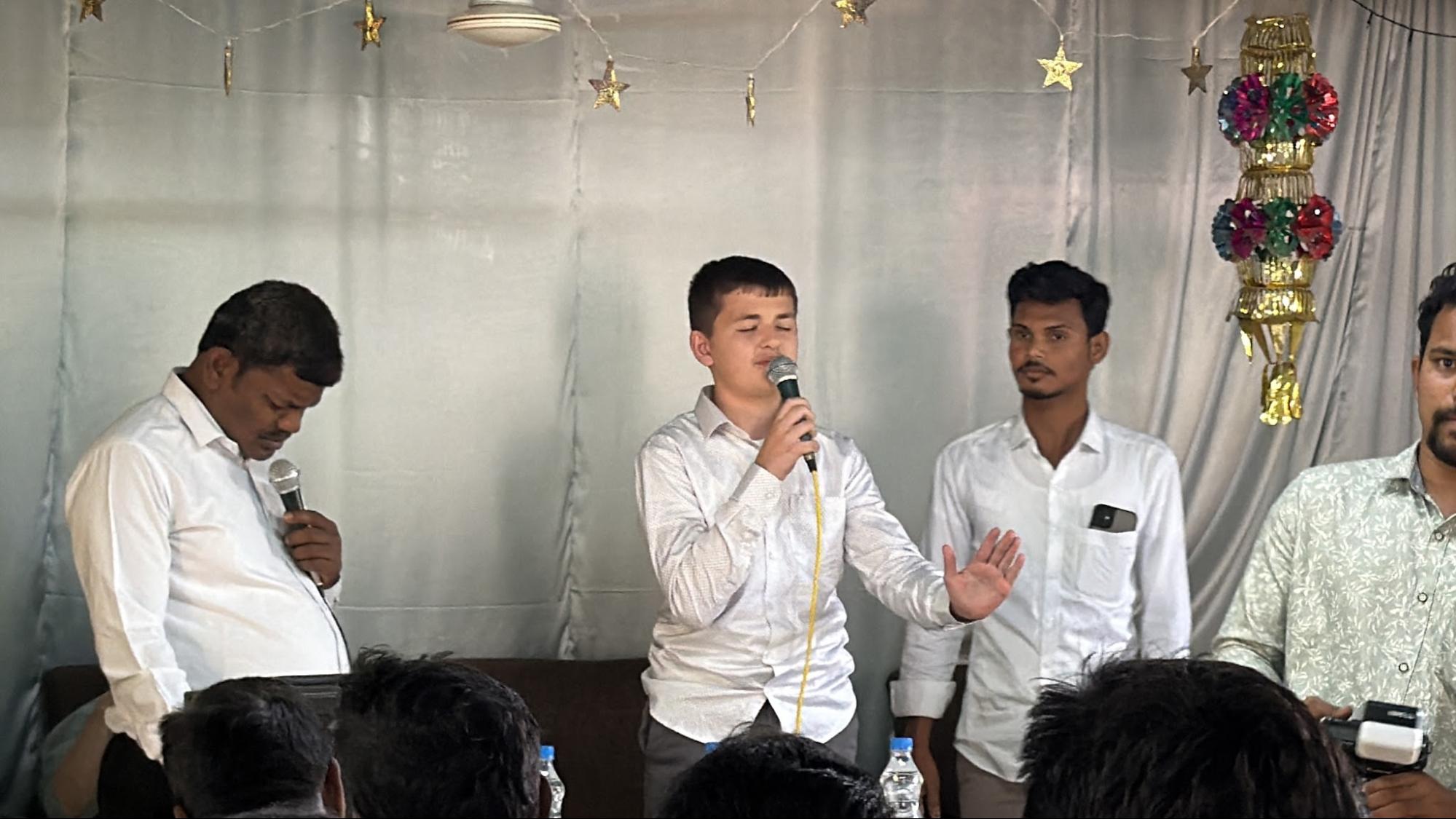 Young team member sharing his testimony with a local pastor translating