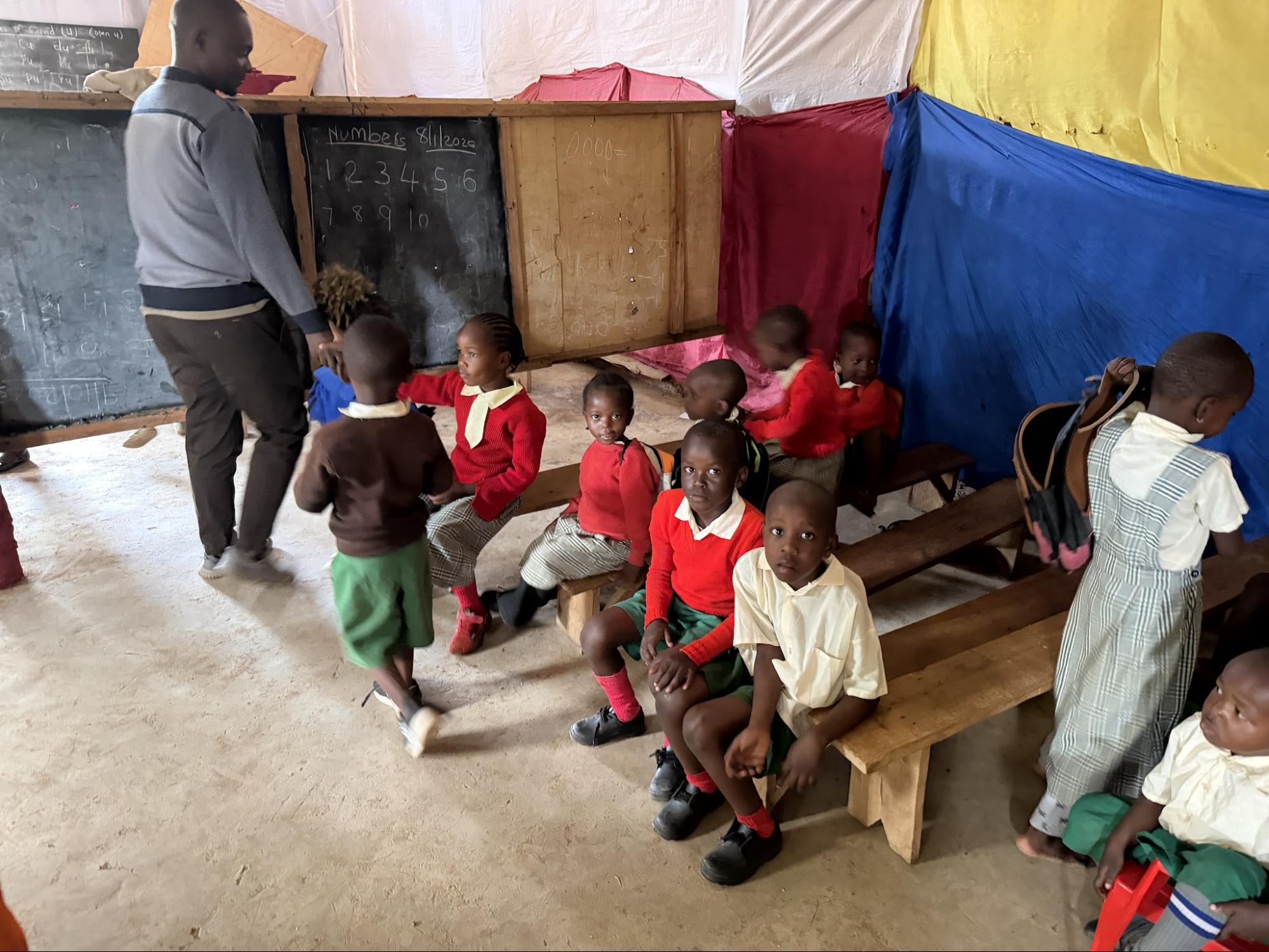 Teacher leading a class of young students in a simple classroom