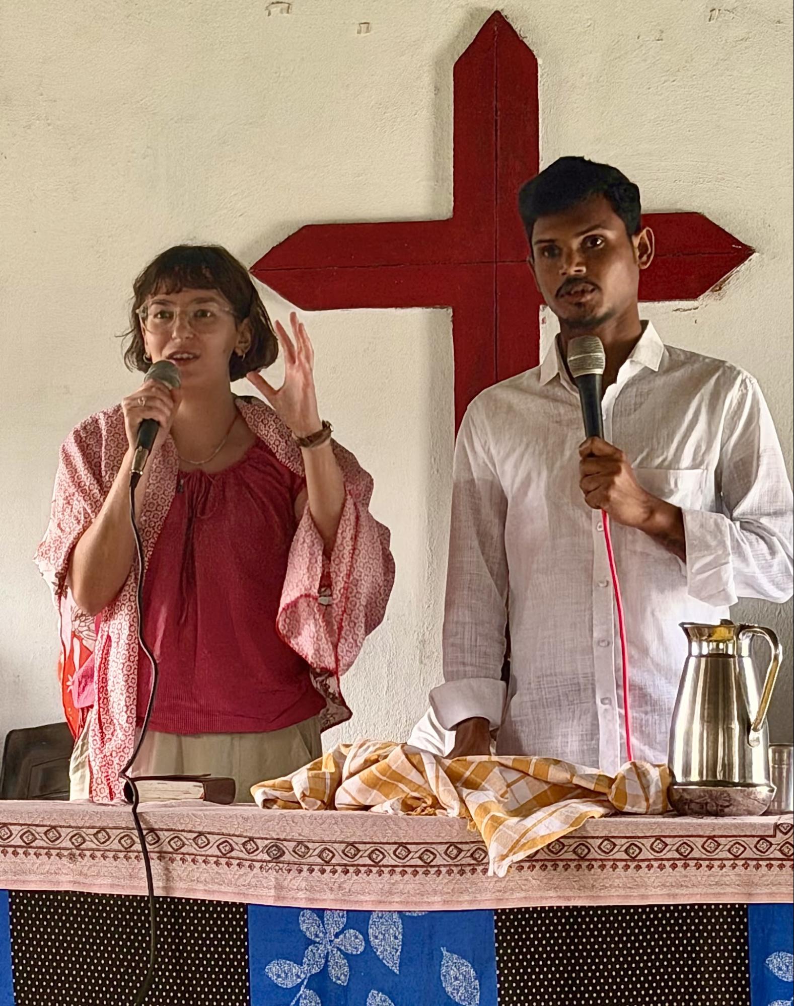 Sharing a message with a translator in front of the church cross
