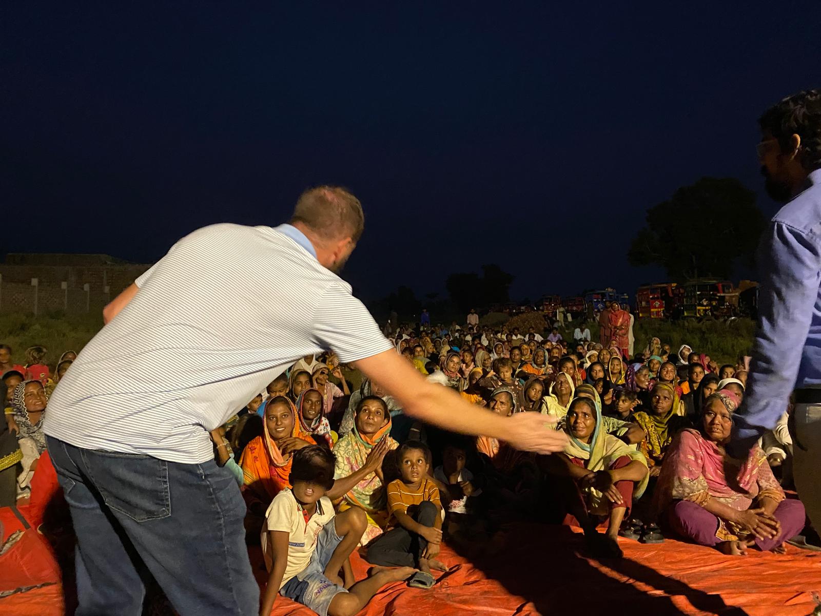 A ministry leader greeting families at an outdoor gathering in Pakistan