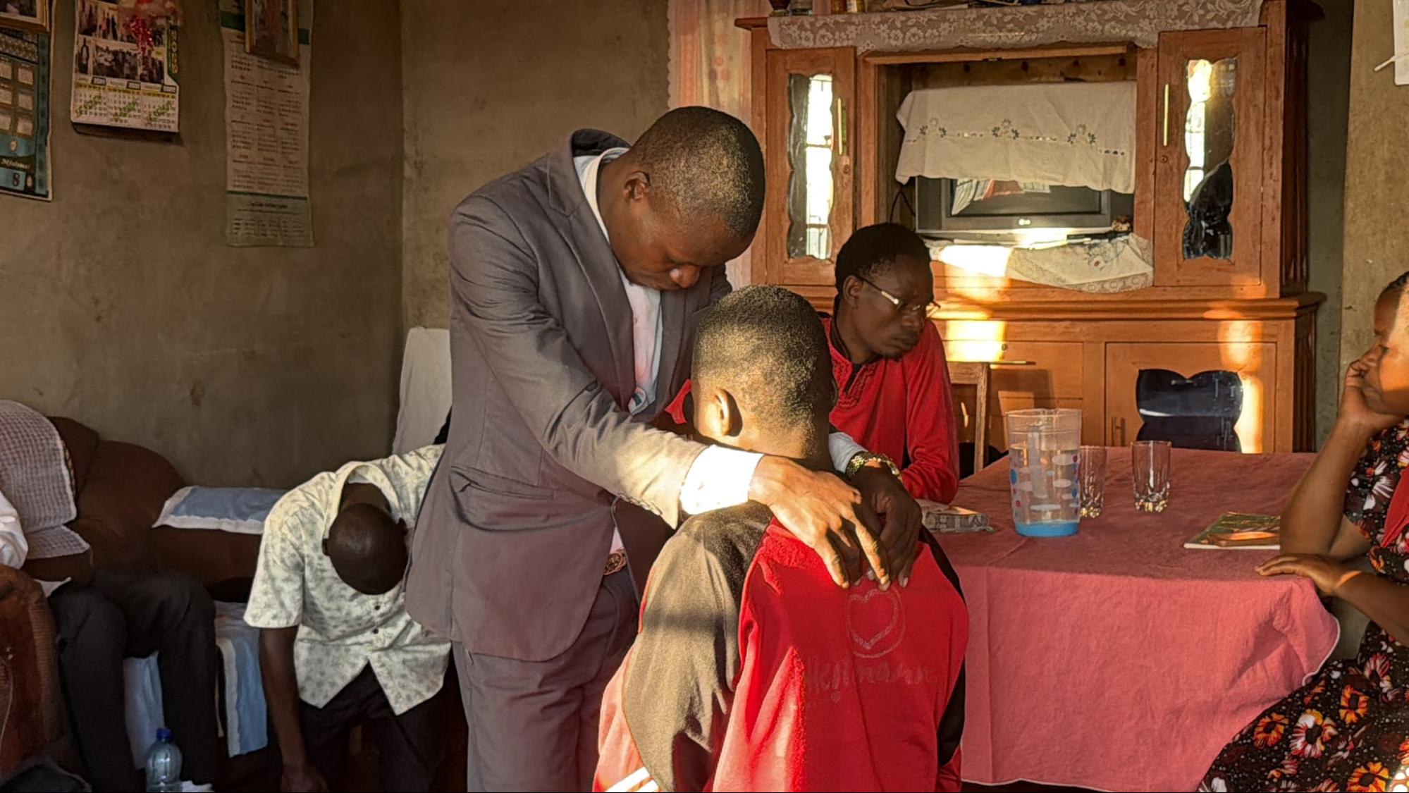 Pastor praying over a young man inside a home