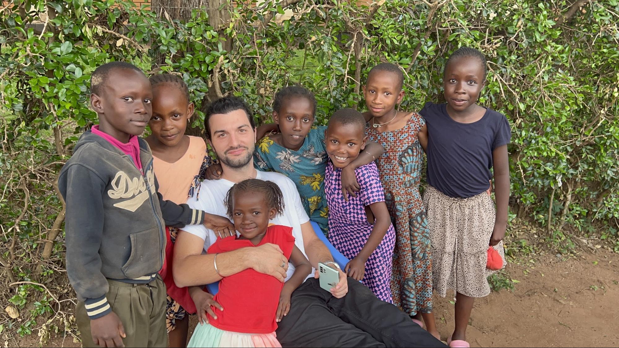 Team member surrounded by smiling children