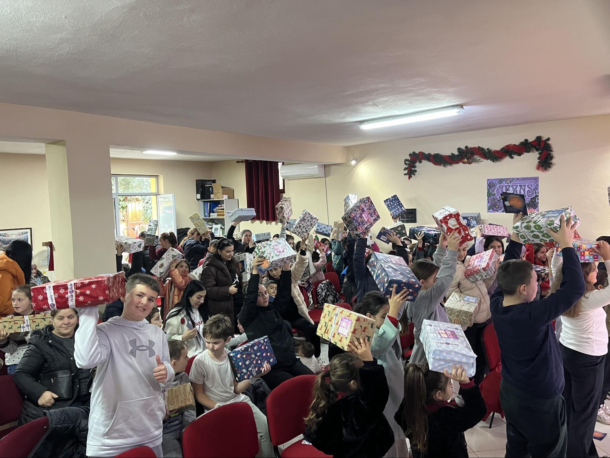 Children and families holding up Christmas gift boxes