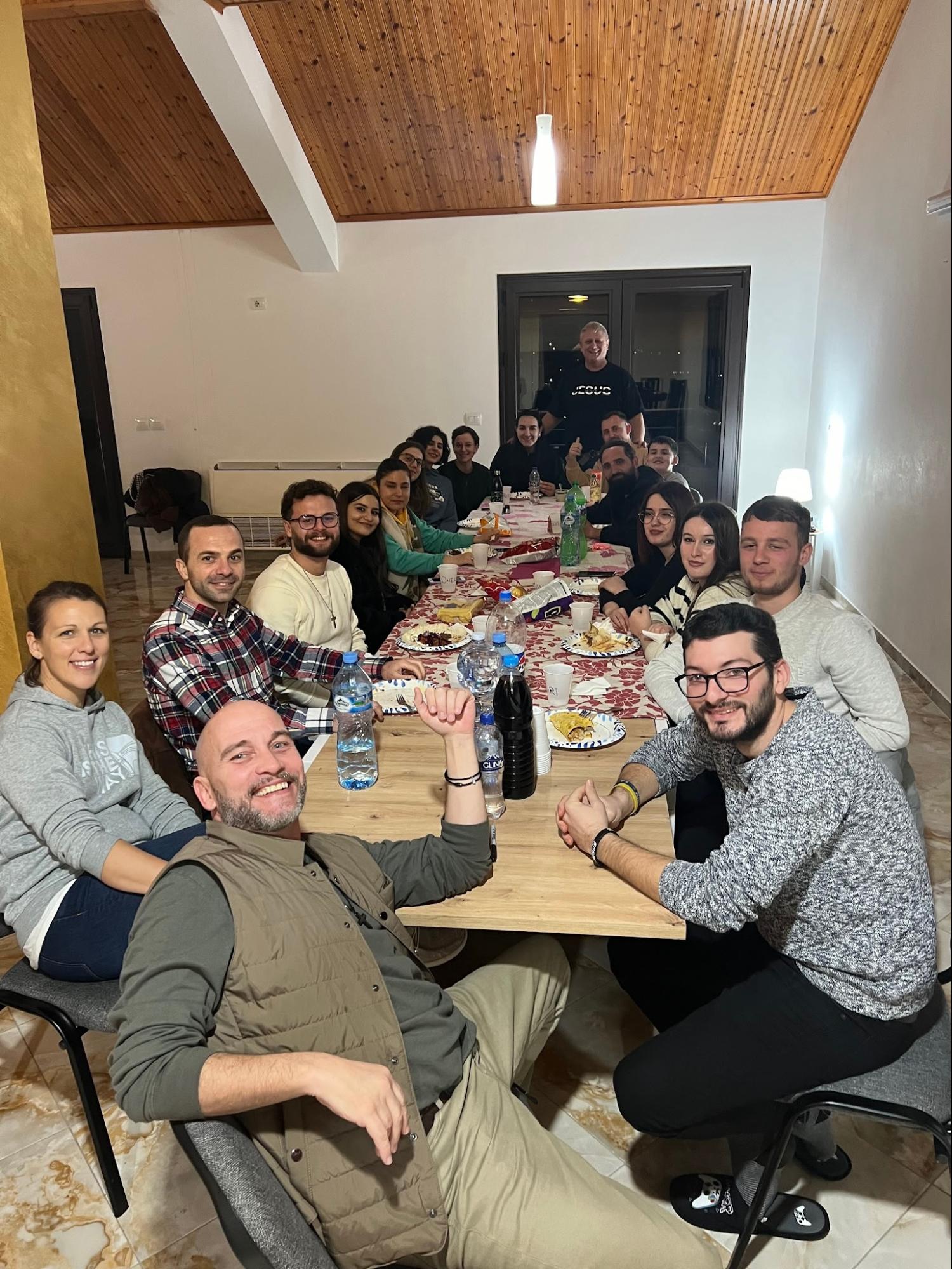 House church members sharing a meal together around a long table in Albania