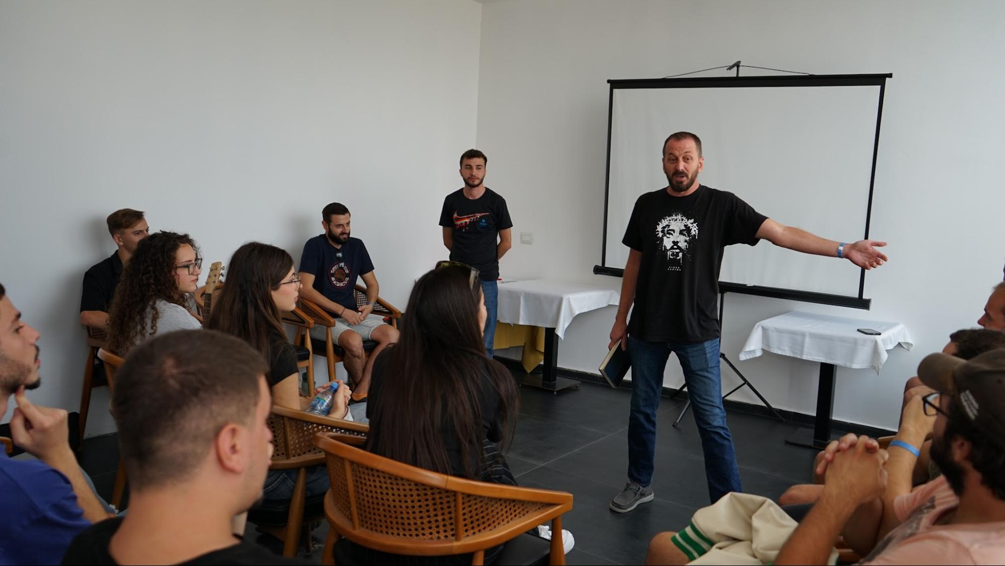 Leader teaching a seated group of young believers in a training room