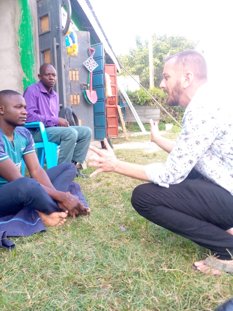 Team member sharing the Gospel with two men outside a home