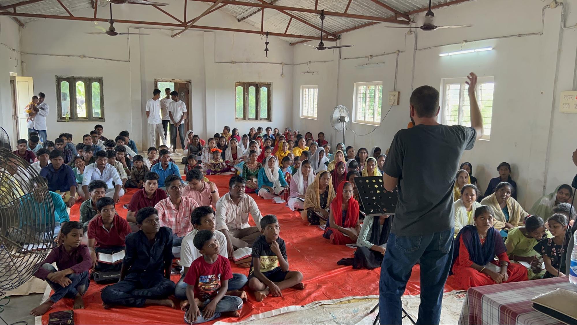 Teaching a packed room of youth and families seated on the floor