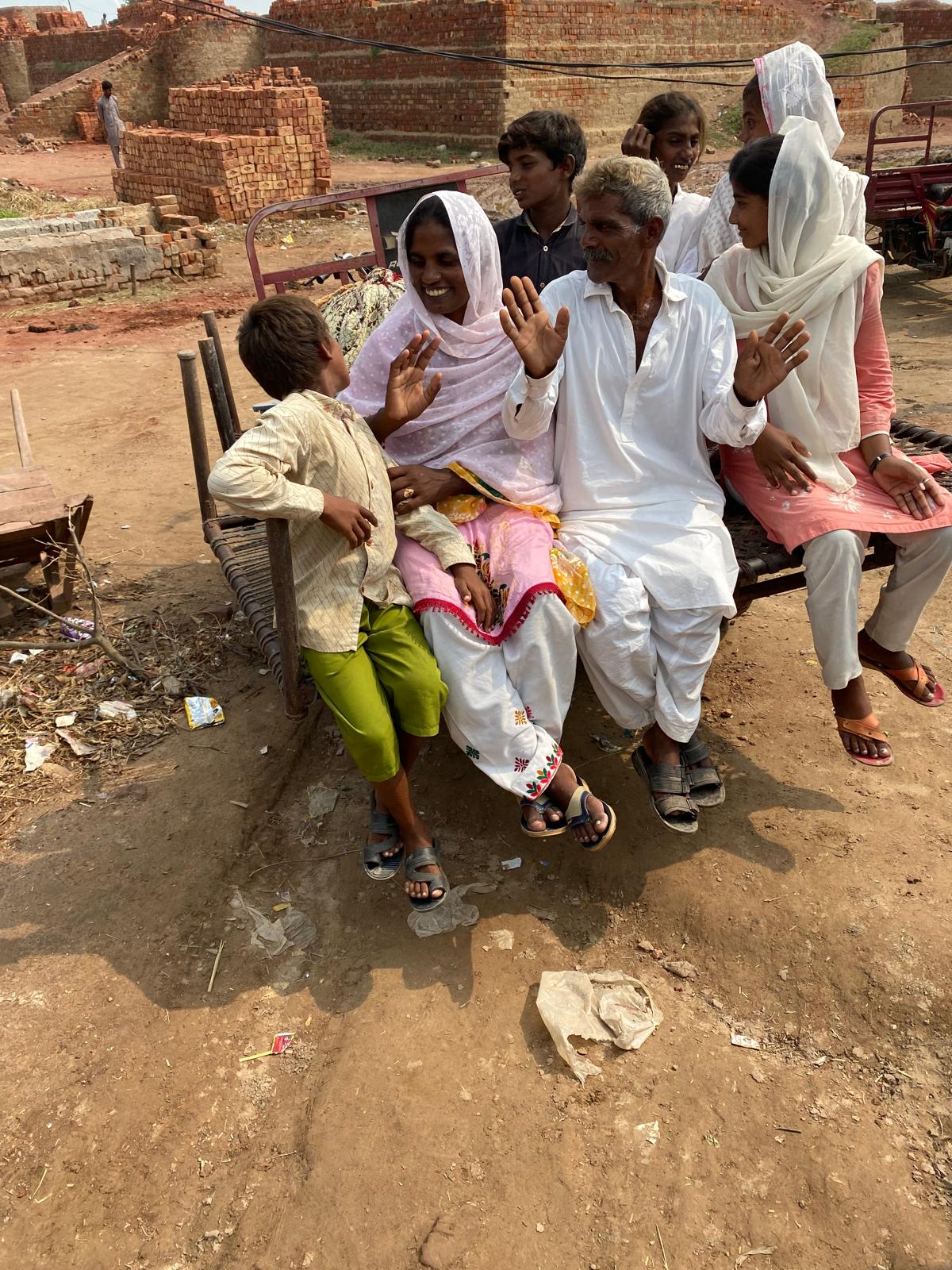A freed family waving together from a cart in a brick-kiln community in Pakistan