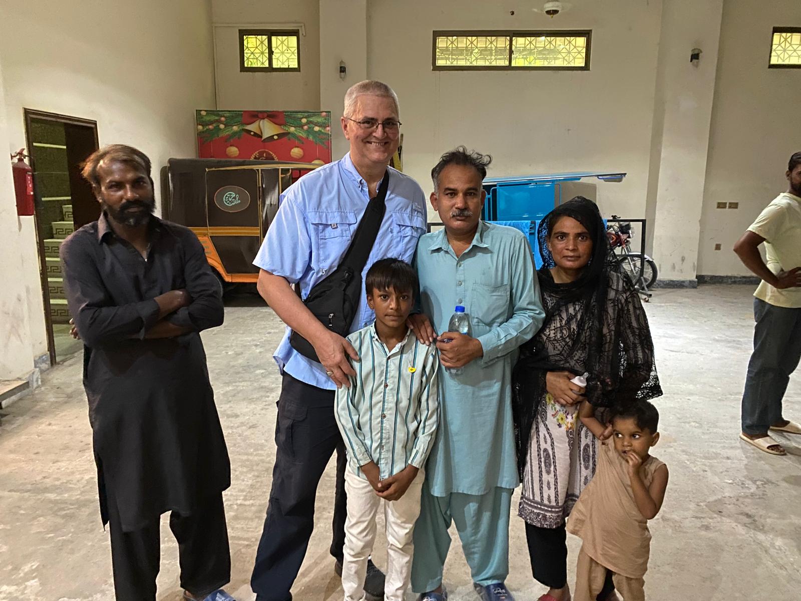 A family and ministry partners gathered beside a rickshaw in Pakistan