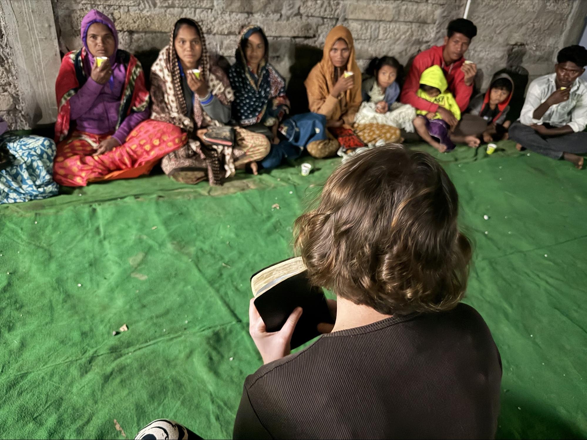 Teaching a small group of families seated on a mat
