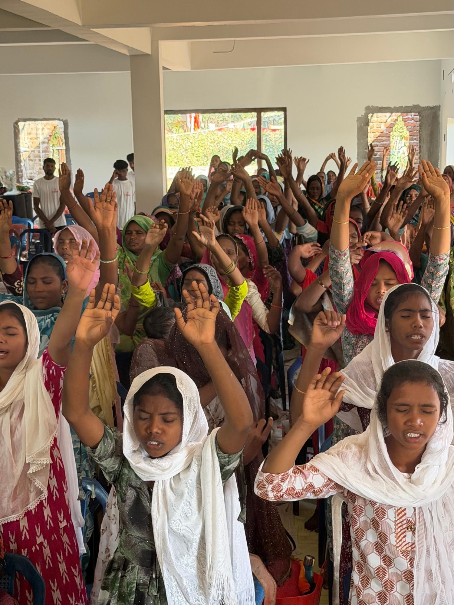 Women worshipping with hands lifted inside the church
