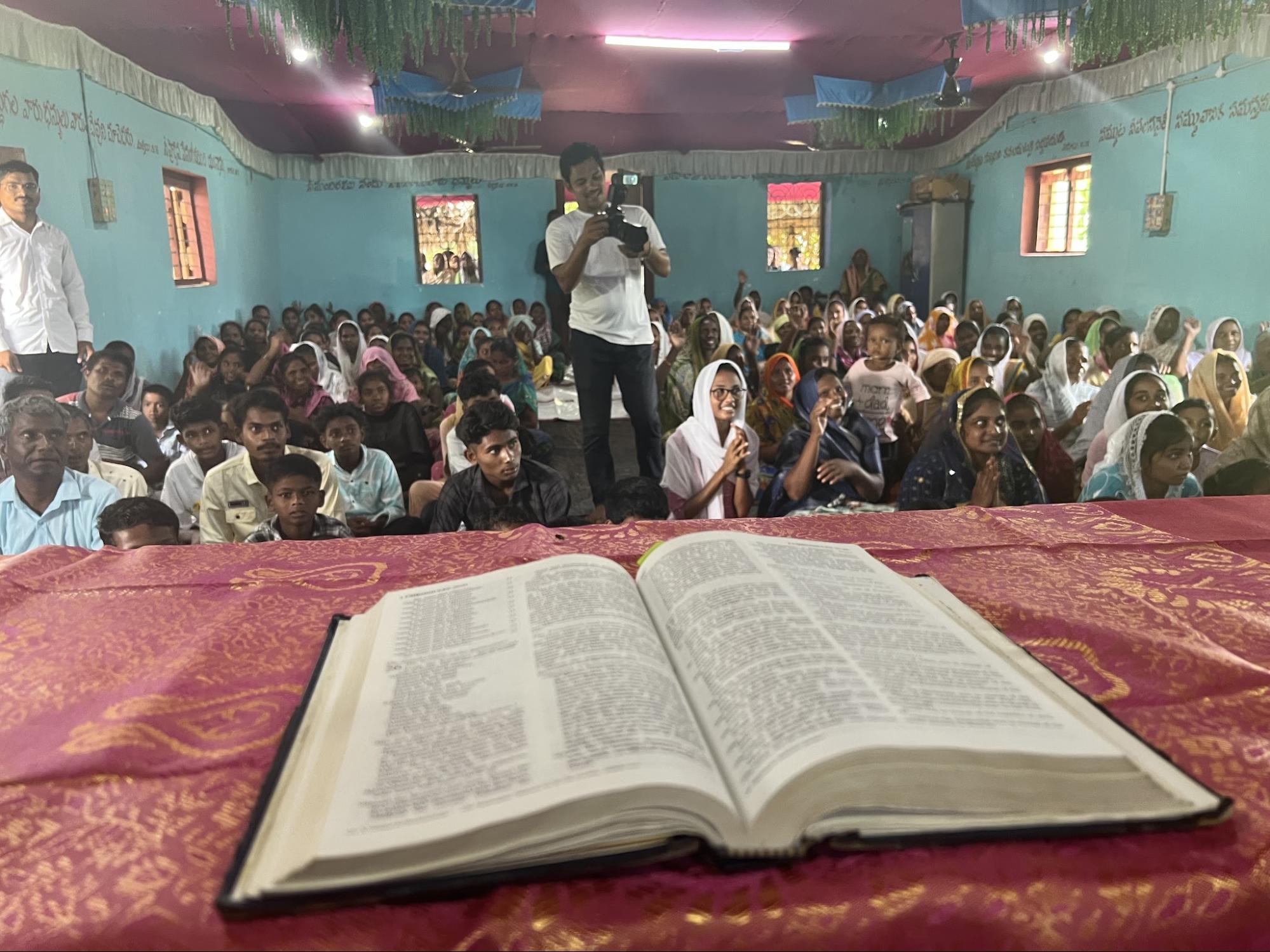 Open Bible on the platform before a packed church gathering