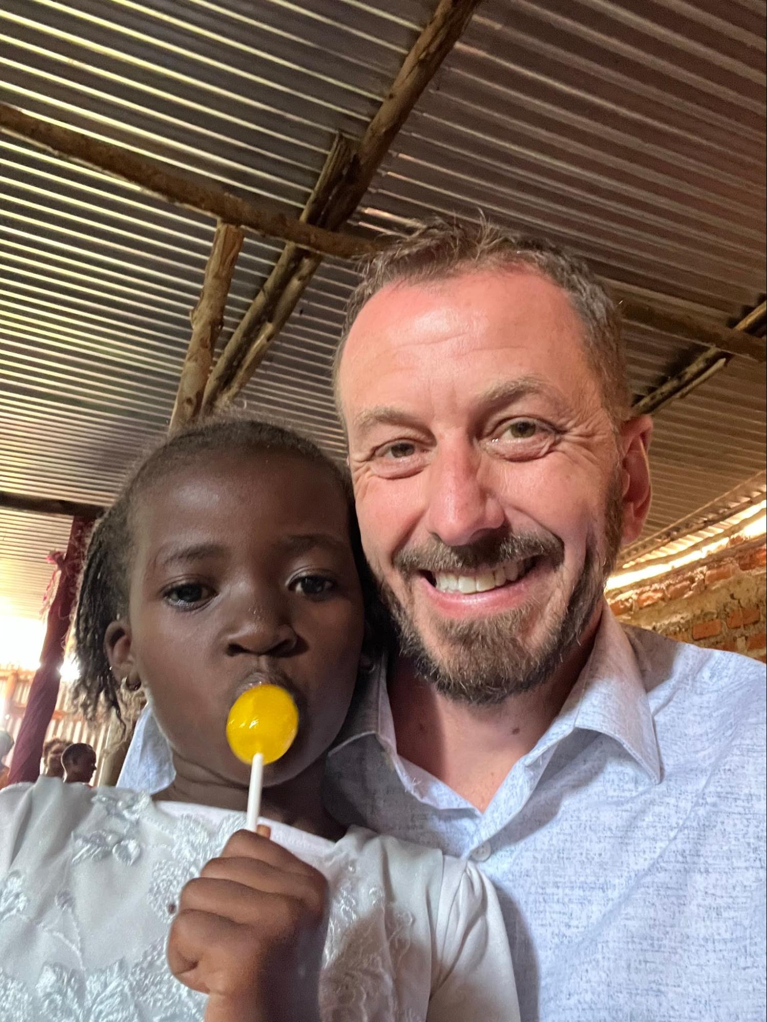 Team member smiling with a young girl holding a lollipop