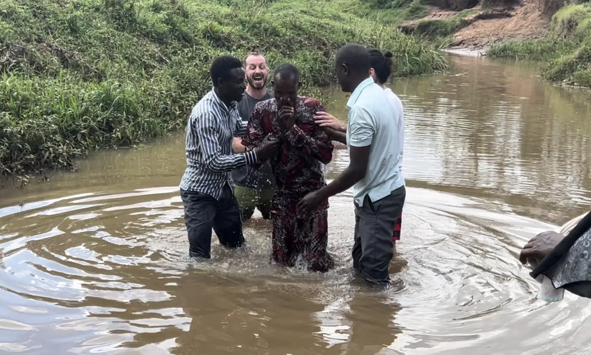 Baptism in a river with local pastors assisting