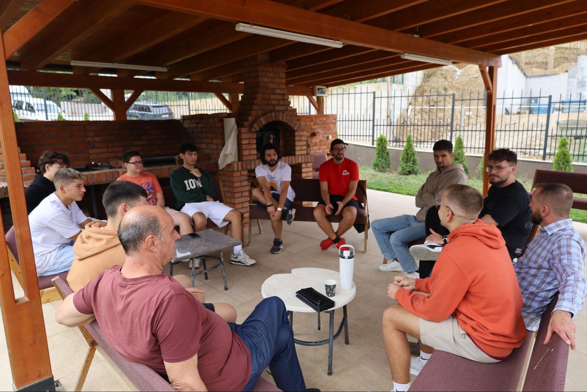 Men gathered in a circle for discipleship under an outdoor pavilion