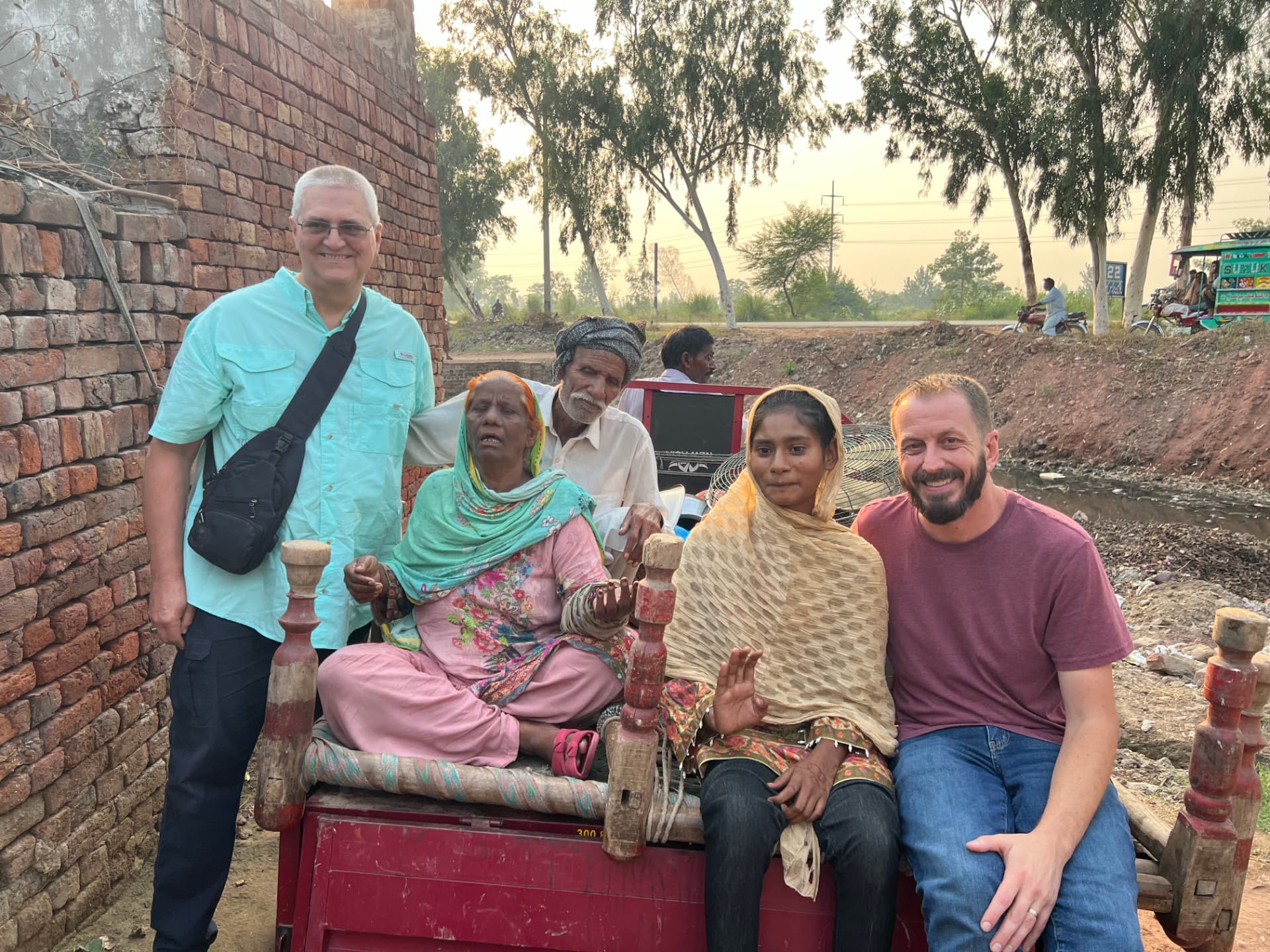 A smiling family and ministry partners gathered on a cart in a brick-kiln community in Pakistan