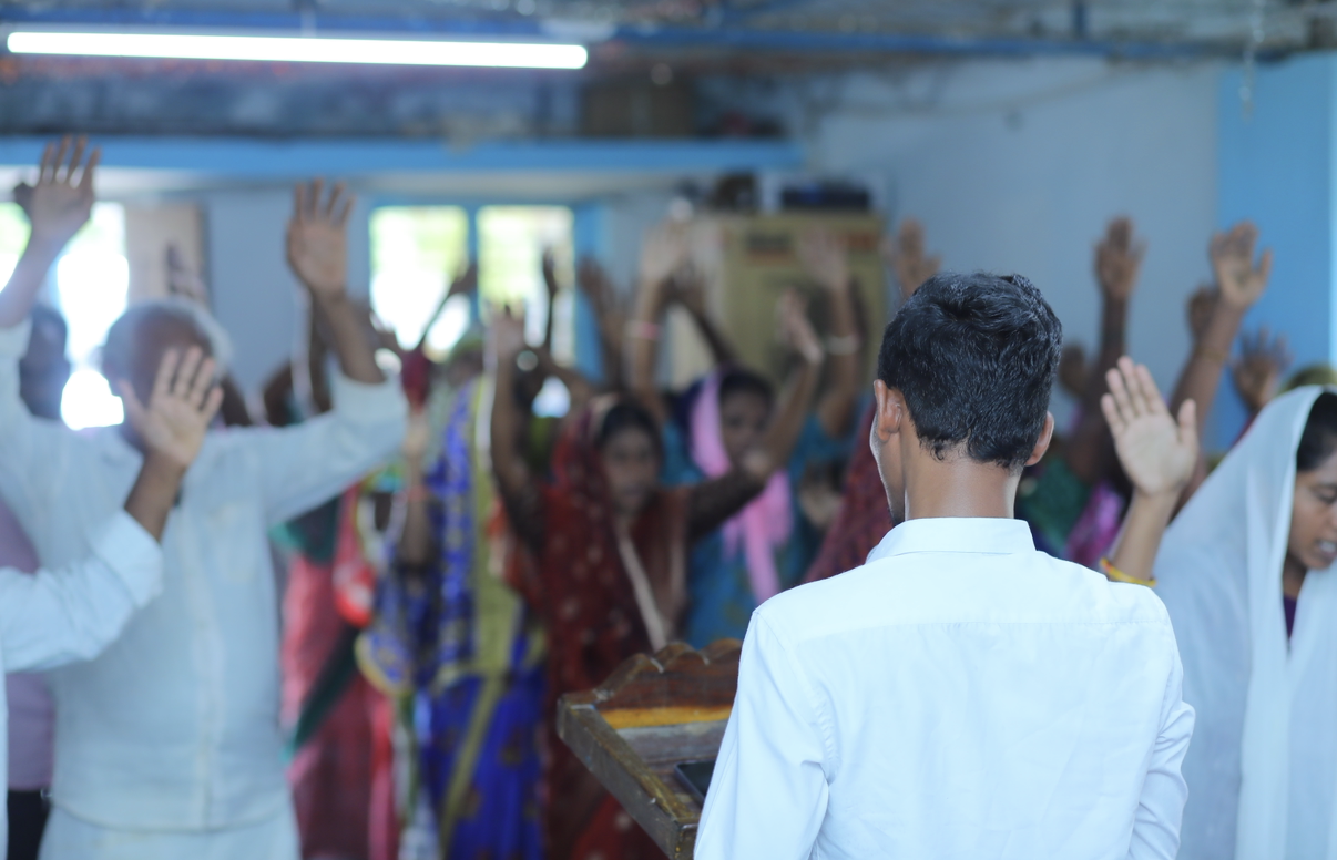 Congregation worshipping with hands raised during a village service