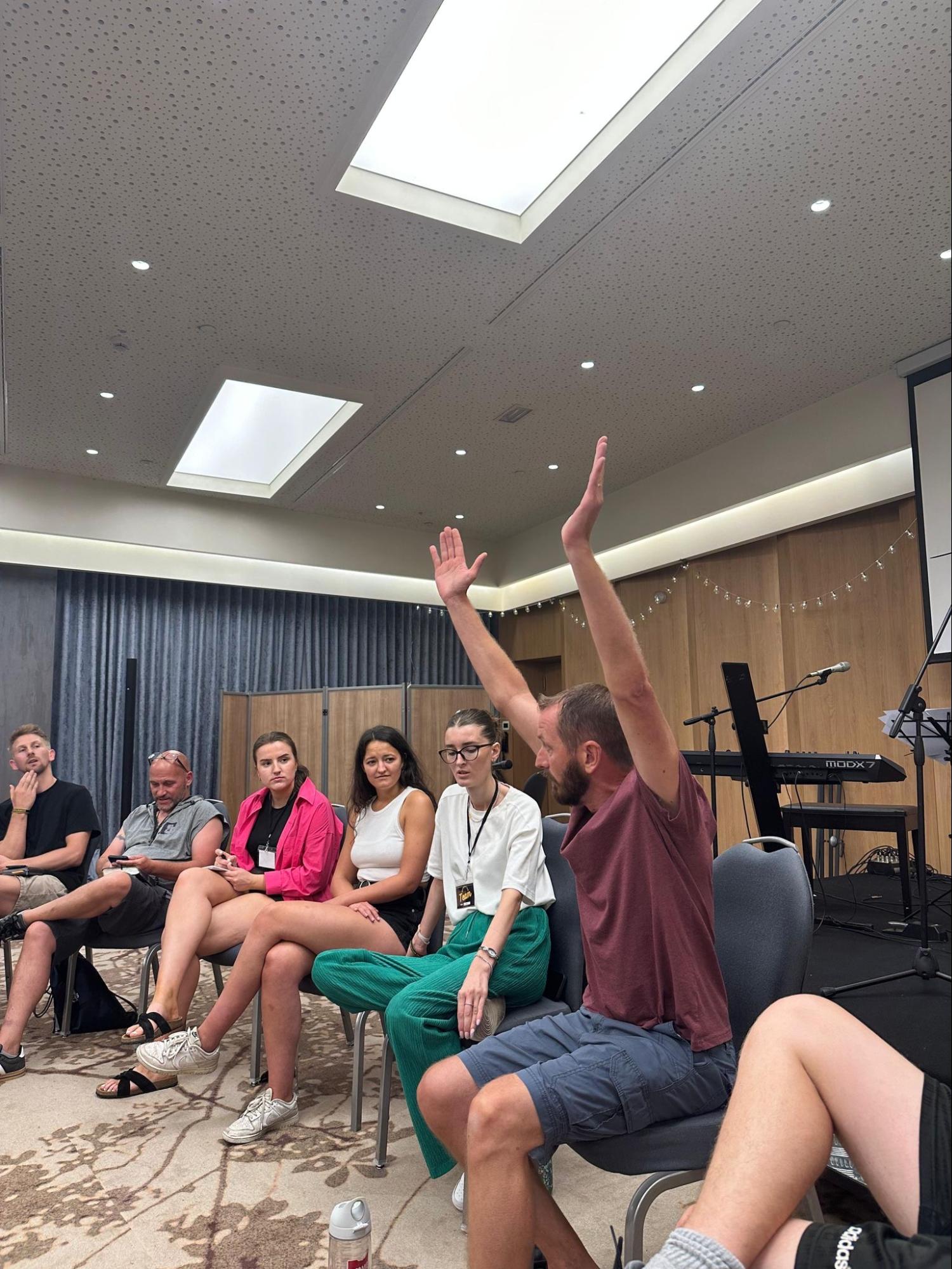 Believer worshipping with hands raised during a conference session