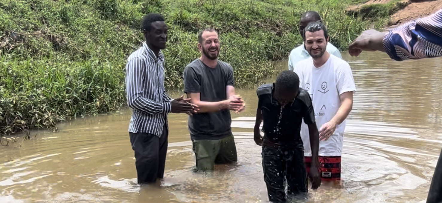 Baptism in a river with team members and local pastors
