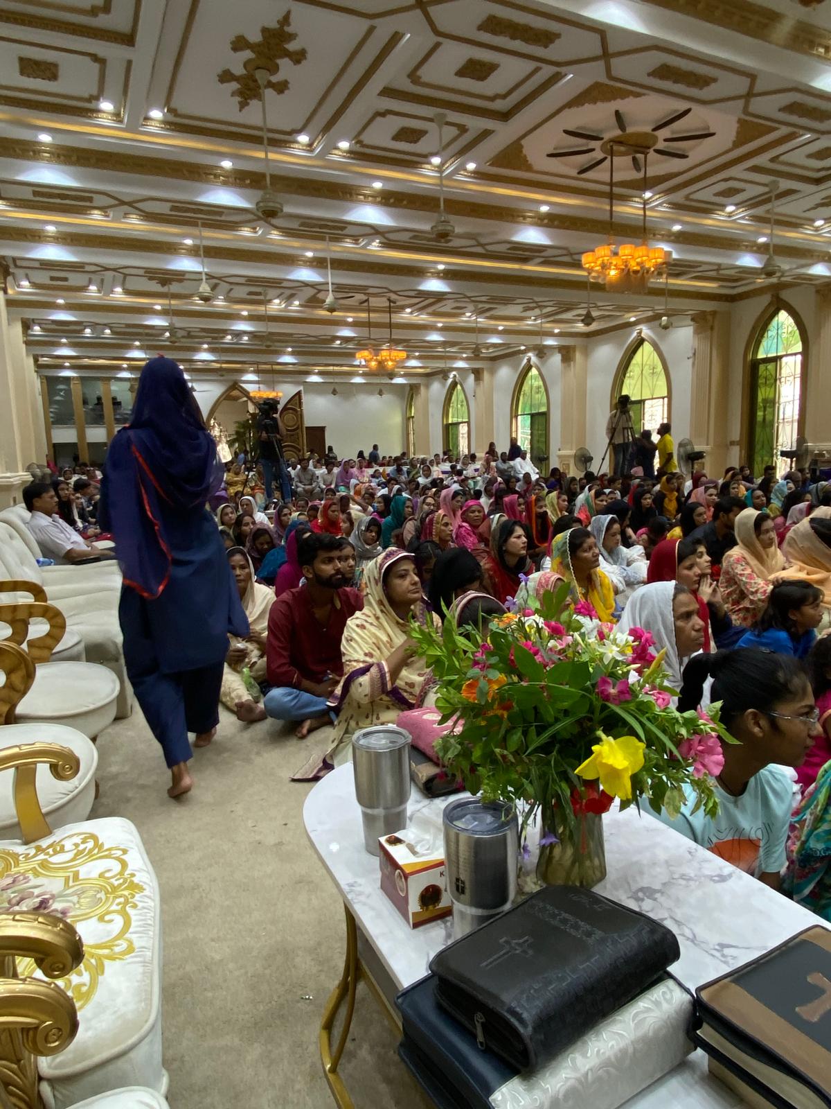 A woman walking to share Scripture inside a decorated hall in Pakistan
