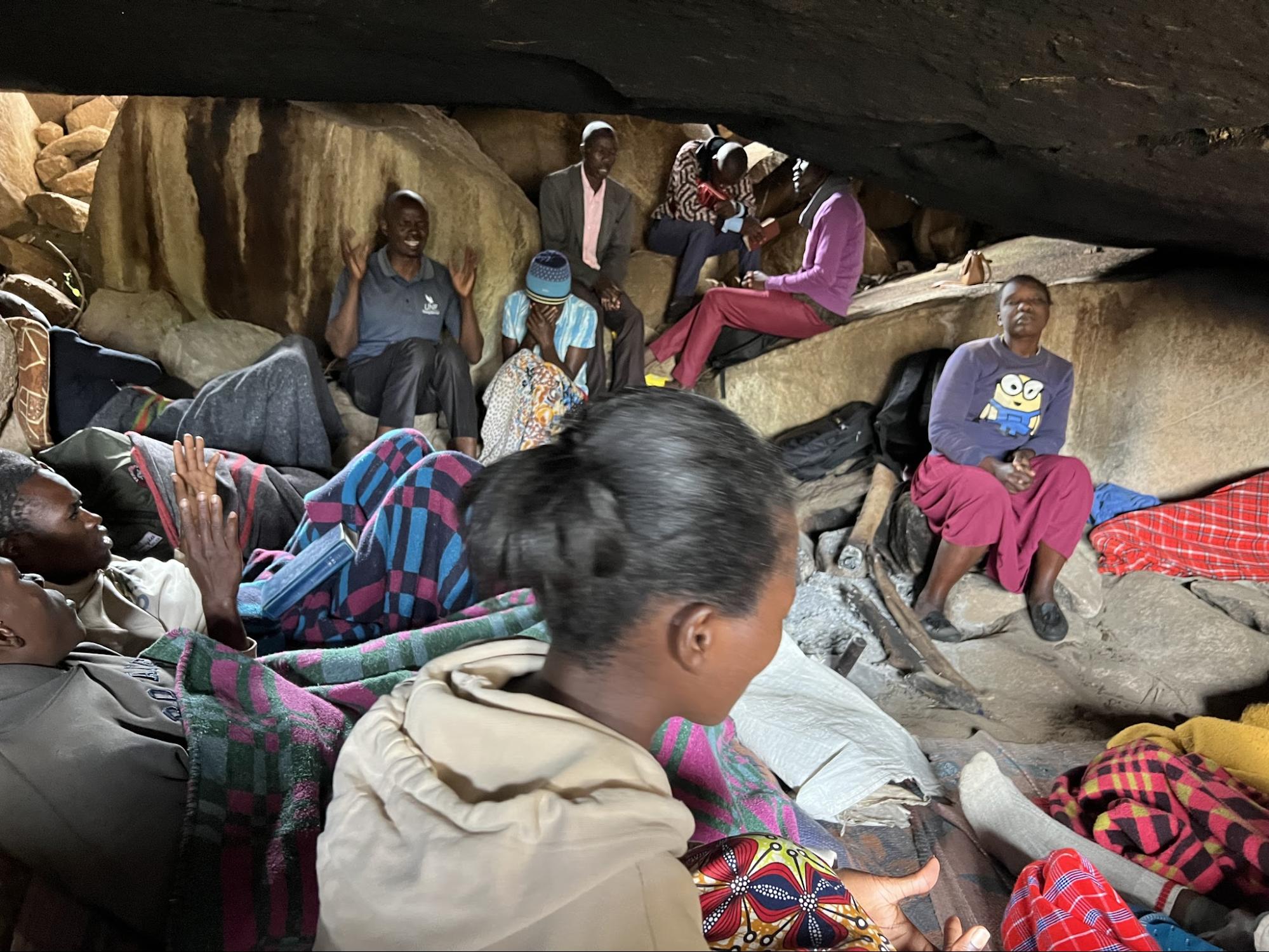 Believers gathered for worship beneath a rock shelter
